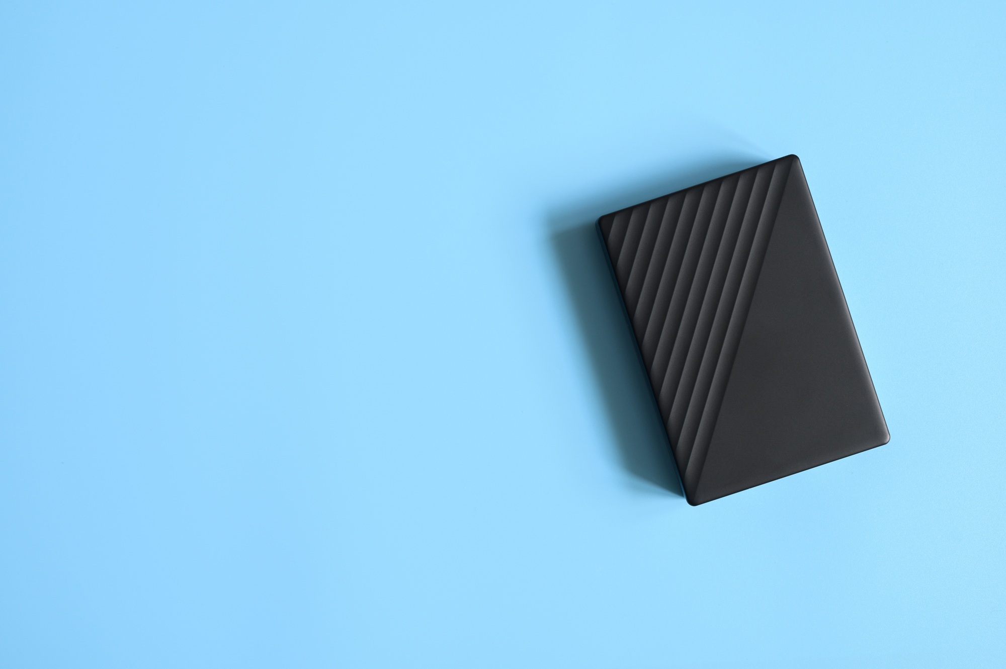 external hard drive black color on blue background. space for text